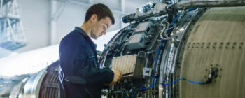 Aircraft Maintenance Mechanic Inspecting and Working on Airplane Jet Engine in Hangar