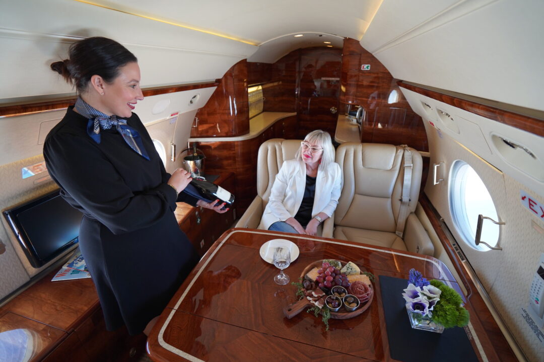 Global Air Charters Cabin attendant showing customer wine bottle scaled