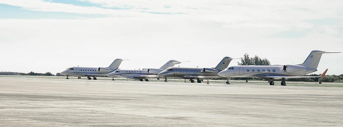4 private jets sitting on tarmac on sunny day